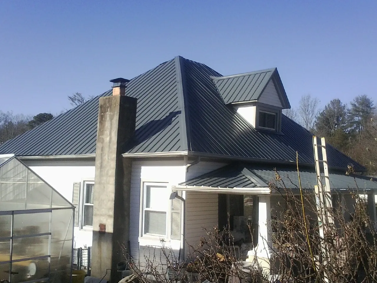 Dark blue standing seam metal roof on a white farmhouse with dormer — Slate & Tile Roof Repair by Roofing Brothers in Tres Pinos