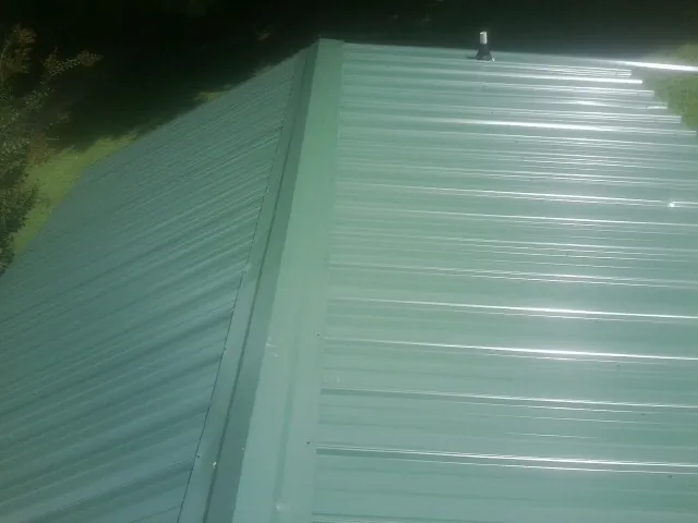 New green metal panels meeting at the ridge of a roof — Flat Roof Repair work by our crew in Tres Pinos