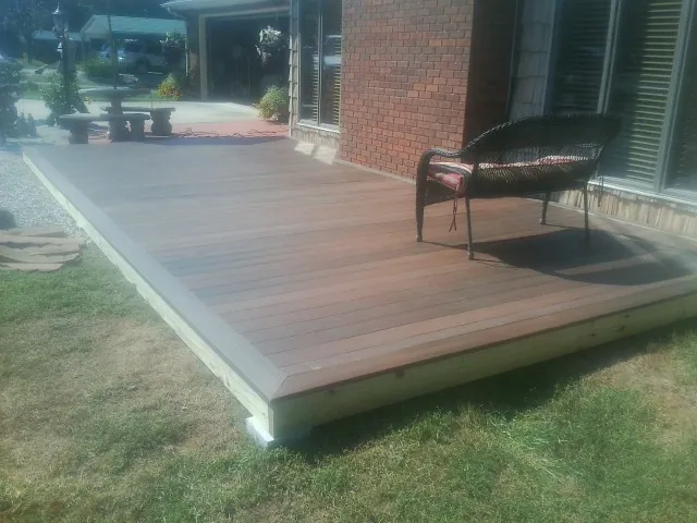 New wood deck and wicker chair beside a brick house in Tres Pinos