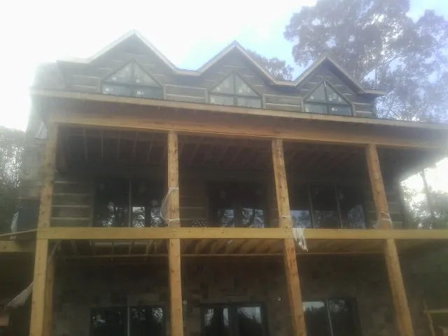 Dormers and porch framing on a large log home under construction — Roof Coating work by our crew in Tres Pinos