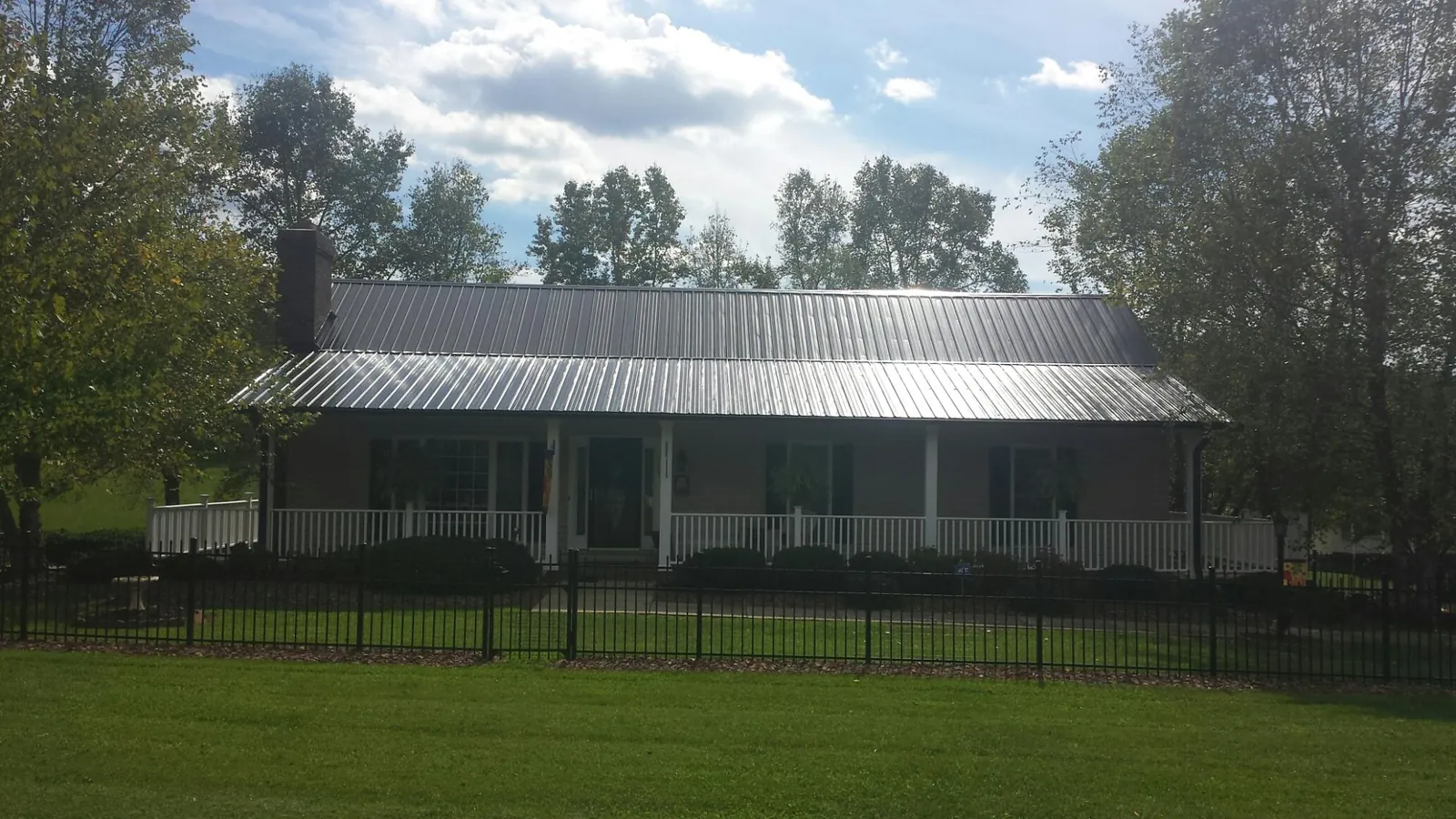 Gray metal roof on a brick ranch with a full width front porch — Gutter Guard Installation work by our crew in Tres Pinos
