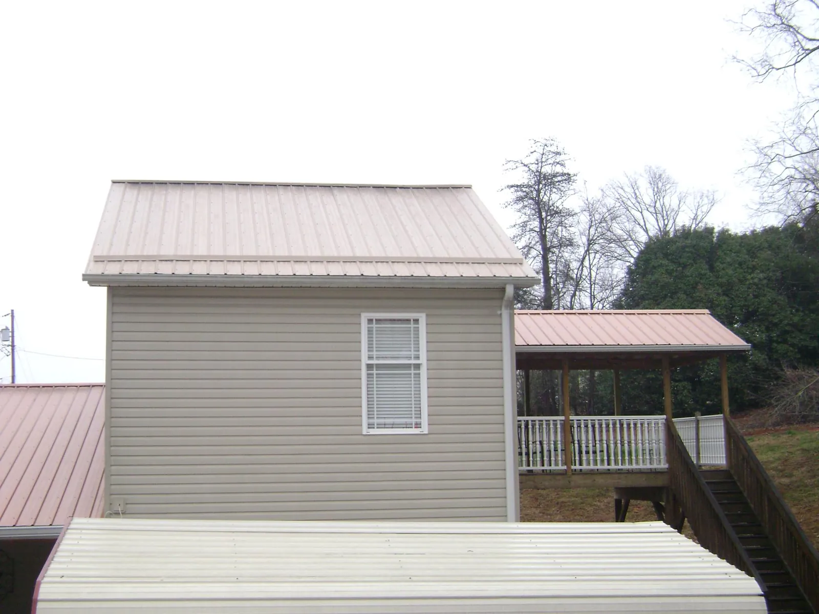 Tan metal roofs on a two story addition and attached porch, from a Roof Replacement job in Tres Pinos