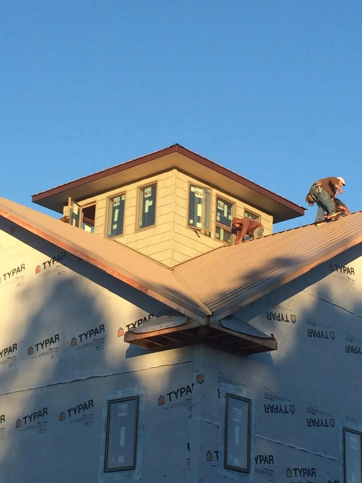 Roofers working around a rooftop cupola on a new metal roof at sunset — Roof Waterproofing in Tres Pinos by Roofing Brothers